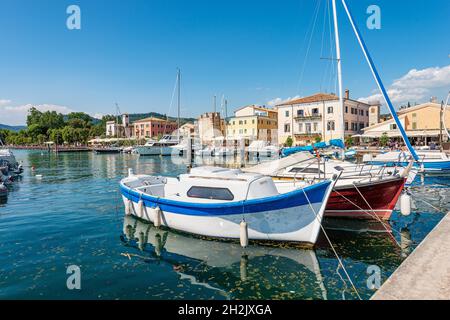 Porto del piccolo borgo di Bardolino con molte barche ormeggiate, località turistica sulla costa del Lago di Garda. Verona provincia, Veneto, Italia, Europa. Foto Stock