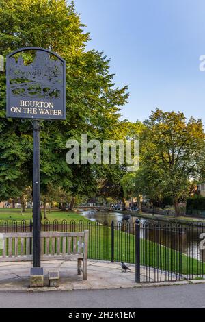 Segno del villaggio di Bourton-on-the-Water, una popolare destinazione Cotswold con il fiume che scorre dolcemente Windrush che attraversa il centro del villaggio. Foto Stock