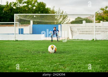 Portiere in un gol pronto a salvare una punizione sparato su un campo di calcio Foto Stock