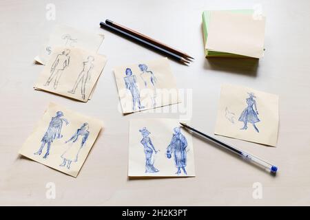 Bozzetti di silhouette alla moda di donna del XX secolo disegnati a mano su fogli di carta su tavolo marrone chiaro Foto Stock