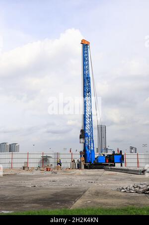 ingegneri e martelli che guidano la macchina su pali che lavorano nell'area di costruzione. Foto Stock