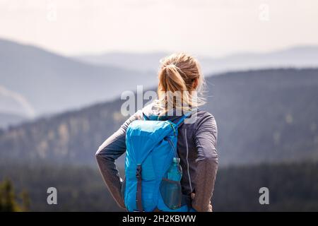 Escursione in montagna. Turista che gode di vista panoramica nella natura. Donna con zaino in piedi al picco della montagna. Stile di vita di viaggio e concetto di avventura Foto Stock