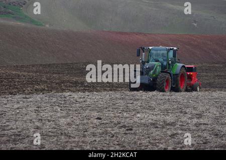 Un trattore lavora i campi prima di seminare nella campagna del basso Molise Foto Stock