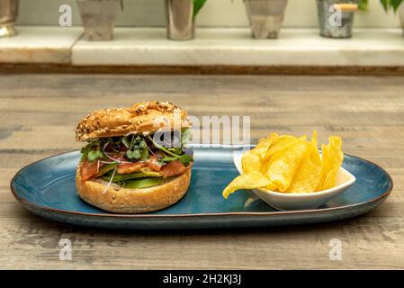 Bagel di pane tradizionalmente a base di farina di frumento, farciti con salmone norvegese affumicato con fette di avocado e germogli di lattuga assortiti guarniti con p. Foto Stock