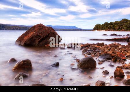 Baia di Platypus sul lago di St Clair all'alba intorno a grandi massi e rocce più piccole sulle rive del lago montano vicino al molo dei traghetti. Foto Stock