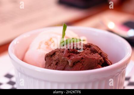 Cucchiai di gelato al cioccolato e alla vaniglia su un recipiente bianco. Dolce dessert concetto Foto Stock