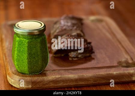 Vasetto con salsa di pesto fresco sul tavolo. Foto Stock