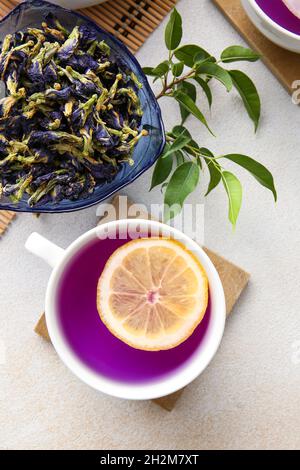 Tazza di tè biologico a farfalla e fiori secchi su sfondo chiaro Foto Stock