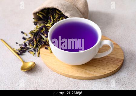 Tazza con tè biologico blu e borsa con fiori secchi di farfalla piselli su sfondo chiaro Foto Stock