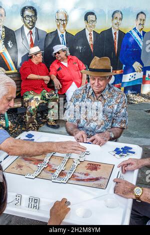 Miami Florida,Little Havana,Calle Ocho,Domino Park Maximo Gomez Park,ispanico cubano adulti uomo uomini maschi che giocano a domino murale Foto Stock