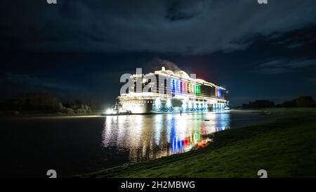 Papenburg, Germania. 23 ottobre 2021. La nave da crociera di 337 metri 'Aidacosma' sarà trasferita attraverso l'EMS al Mare del Nord durante la notte. Il colosso da crociera di nuova costruzione 'Aidacosmaa' ha iniziato il suo rimorchiatore dal cantiere Meyer sull'EMS al Mare del Nord. Credit: Mohssen Assanimoghaddam/dpa/Alamy Live News Foto Stock