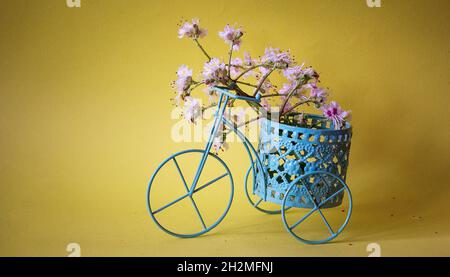 Bicicletta d'epoca con un cesto di fiori su sfondo giallo Foto Stock