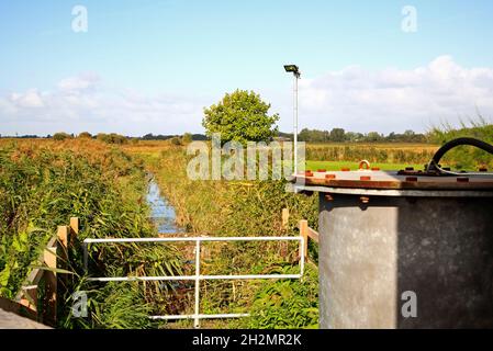 Una diga di drenaggio delle paludi che porta ad una piccola stazione di pompaggio per controllare i livelli dell'acqua sui Norfolk Broads a Thurne, Norfolk, Inghilterra, Regno Unito. Foto Stock