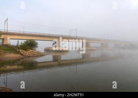 Il ponte ferroviario sparisce nella nebbia. Foto Stock