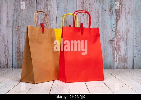 Sacchetti di carta colorati su un elegante tavolo di legno per il vostro shopping gioioso. Spazio per il logo o la scrittura sul sacchetto rosso e marrone. Foto Stock