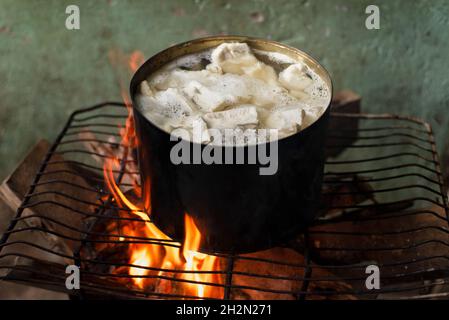 Manioca che viene cucinata in padella di ferro con fuoco di legno sulla parte superiore di una griglia. Salvador Bahia Brasile. Foto Stock