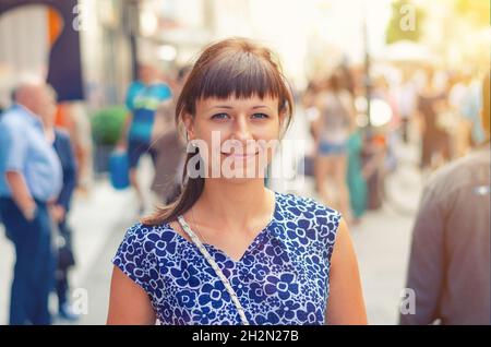 Primo piano ritratto di giovane bella ragazza caucasica con camicia fiorita guardando la macchina fotografica e il sorriso nella strada pedonale della città storica di Vienna Foto Stock