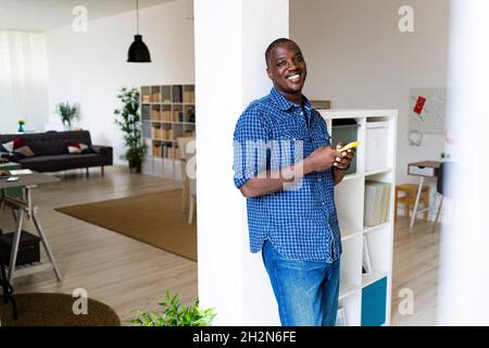 Uomo felice che naviga in rete tramite smartphone a casa Foto Stock