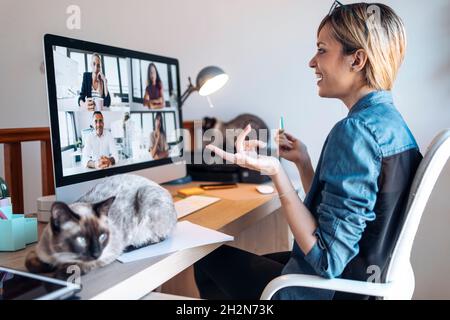 Vlogger femminile medio adulto gesturing durante la videoconferenza a casa Foto Stock