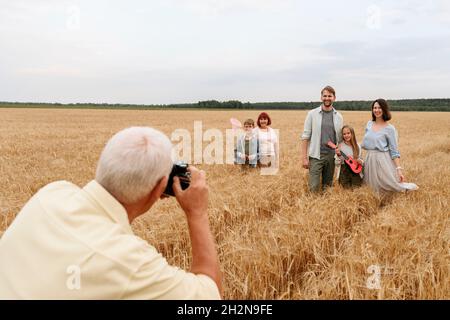 Uomo che fotografa attraverso la macchina fotografica sul campo di grano Foto Stock