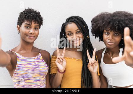 Amici femminili con braccia incrociate appoggiate sul muro Foto Stock
