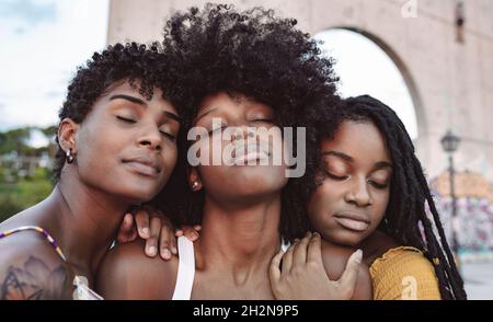 Sorridendo giovani amici femminili che si appoggiano sulla donna Foto Stock