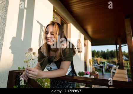 Donna che guarda il thistle del globo mentre si appoggia sulla ringhiera durante la giornata di sole Foto Stock