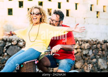 Uomo felice in bicicletta con donna matura e allegra seduta sul cesto della bicicletta Foto Stock