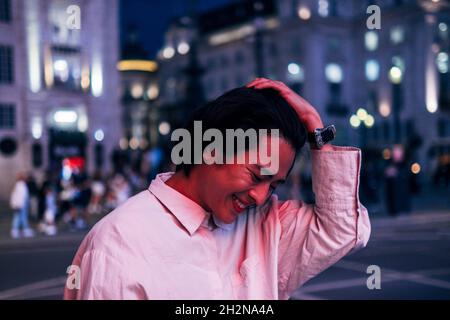 Ragazzo allegro con mano in capelli di notte Foto Stock
