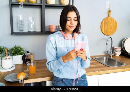 Felice giovane donna che tiene il tablet digitale sul banco della cucina Foto Stock