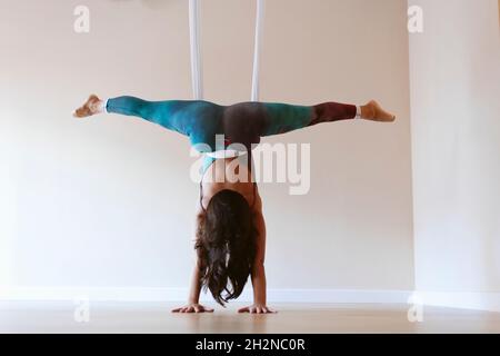 Ginnasta femminile che fa verticale con amaca yoga aerea allo studio  sportivo