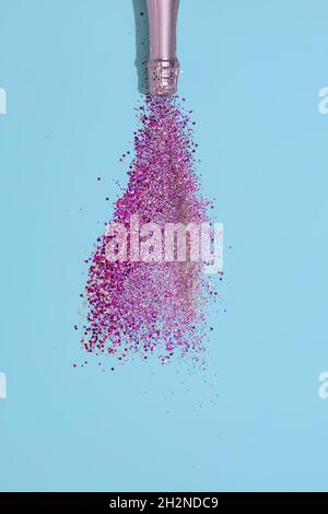 Bottiglia di champagne con schizzi di confetti su sfondo di carta blu. Festa di San Valentino Foto Stock