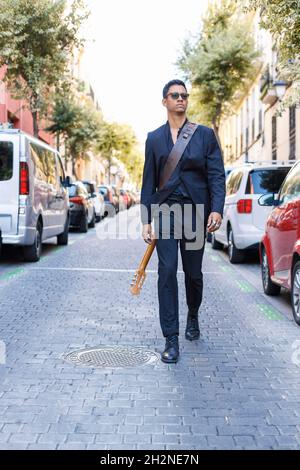 Sorridente giovane musicista maschile che suona la chitarra a muro Foto Stock