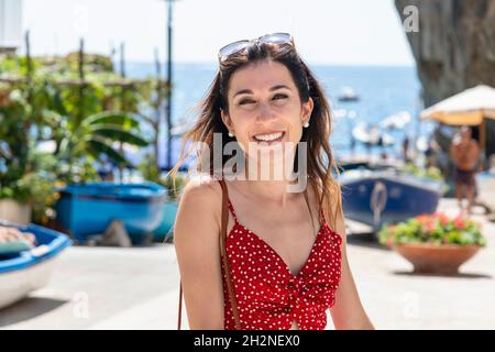 Donna sorridente in abito rosso estivo in spiaggia Foto Stock