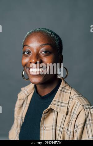 Felice giovane donna in anello d'oro orecchino in studio Foto Stock