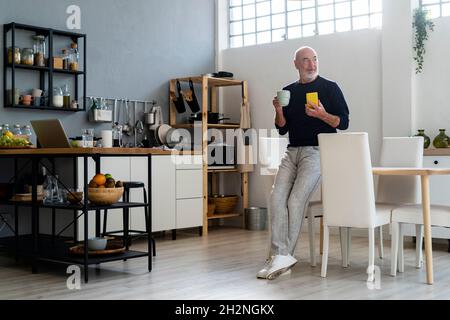 L uomo un caffè mentre si utilizza il telefono cellulare a casa Foto Stock