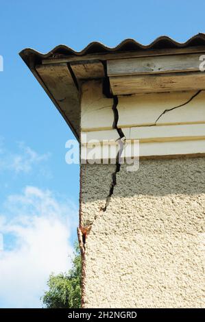 Angolo muro stucco danneggiato. Muro incrinato vicino Roof Construction. Dettaglio di casa danneggiato angolo dilapidato vecchio edificio facciata muro. Privato ab Foto Stock