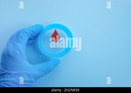 Consapevolezza del giorno del diabete mondiale. Mano che tiene il cerchio blu con goccia di sangue. Foto Stock