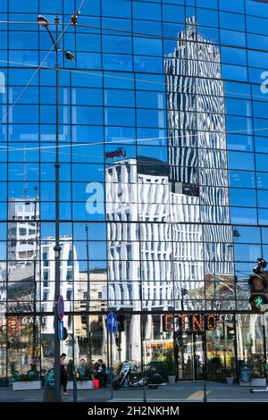 Lodz, Polonia - 9 settembre 2021: Riflessi della vita cittadina in un moderno grattacielo di vetro Foto Stock