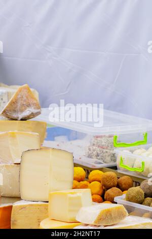 Formaggio di capra duro sul tavolo. Molte varietà di formaggi artigianali sono sul banco durante il festival del formaggio. Concetto di vendita di prodotti lattiero-caseari Foto Stock