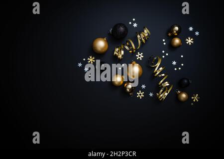 Decorazioni natalizie in nero e oro: Baubles, stelle e nastro su sfondo nero. Foto Stock
