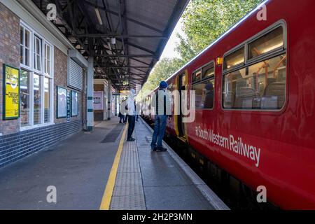 South Western Railway Commuter Train in attesa di salire a bordo dei passeggeri presso la stazione di Epsom Surrey Inghilterra Regno Unito con persone in piedi sul binario Foto Stock