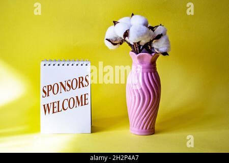 BENVENUTO SPONSOR parole scritte su blocco note con bouquet di cotone Foto Stock