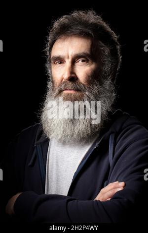 Ritratto di un uomo anziano con una barba grigia su sfondo nero. Foto Stock