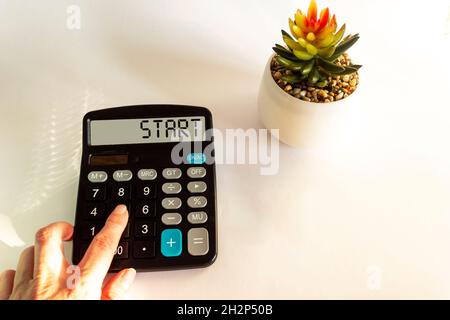 Una calcolatrice con il testo Start sul display. Concetto commerciale e finanziario Foto Stock