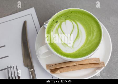 Tazza di latte matcha. Foto di alta qualità. Matcha, latte di tè verde in una tazza. Sfondo di pietra grigia. Primo piano. Vista dall'alto. Foto Stock