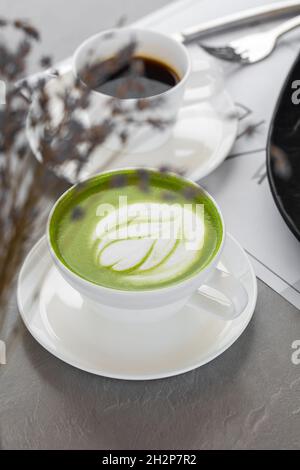 Tazza di latte matcha e caffè. Foto di alta qualità. Matcha, latte di tè verde in una tazza. Sfondo grigio. Primo piano. Vista dall'alto. Foto Stock