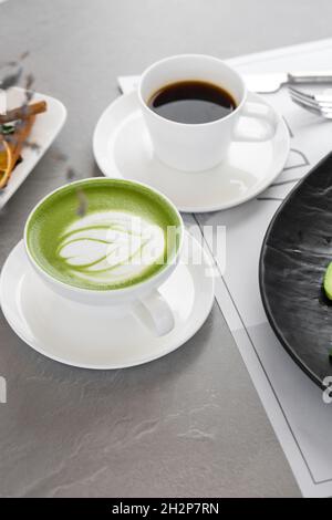 Tazza di latte matcha e caffè. Foto di alta qualità. Matcha, latte di tè verde in una tazza. Sfondo grigio. Primo piano. Vista dall'alto. Foto Stock