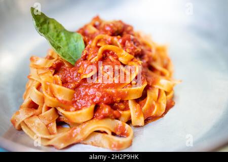 Tagliatelle al sugo di bolognese con foglia di basilico. Foto Stock