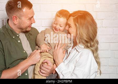 La famiglia felice posa per la foto abbracciante e sorridente dolcemente Foto Stock